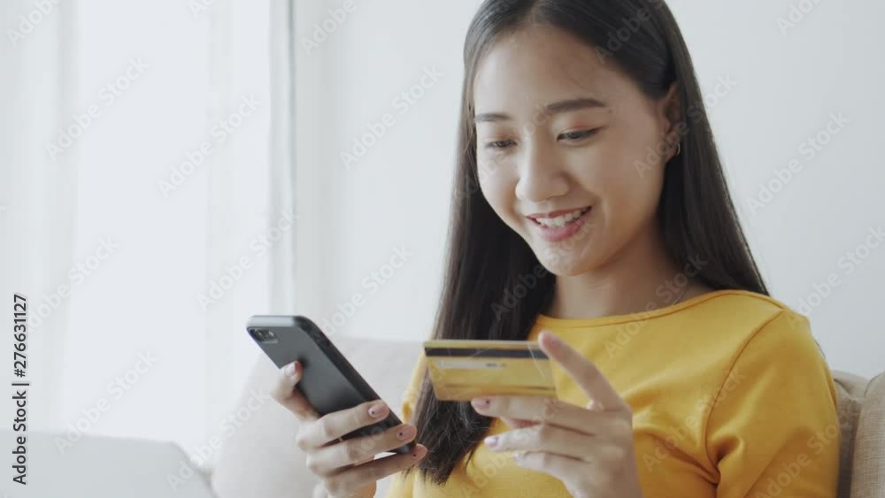 portrait of Beautiful young Asian women are buying online with a credit card. asia girl are using smartphone and making online transactions in the living room at home. portrait of Beautiful young Asian women are buying online with a credit card. asia girl are using smartphone and making online transactions in the living room at home.