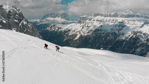 Two traveling women walking upwards on the snowy mountain - Dolomites, Italy © KONSTANTIN SHISHKIN