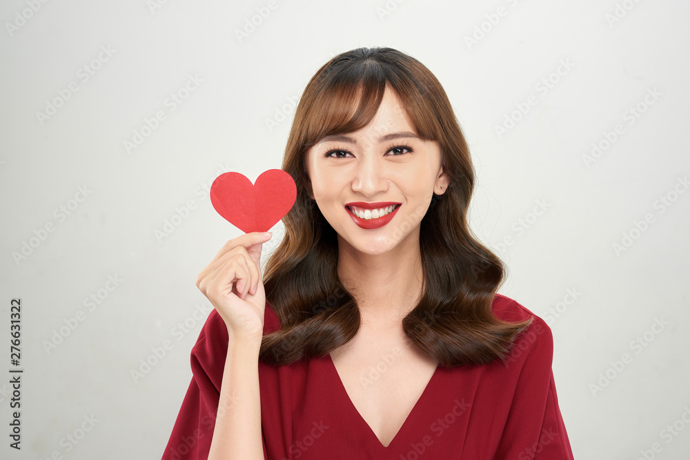 Pretty young Asian woman holding white paper heart and smiling happily at camera Pretty young Asian woman holding white paper heart and smiling happily at camera