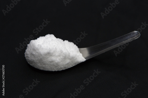 Sea salt in spoon on black background