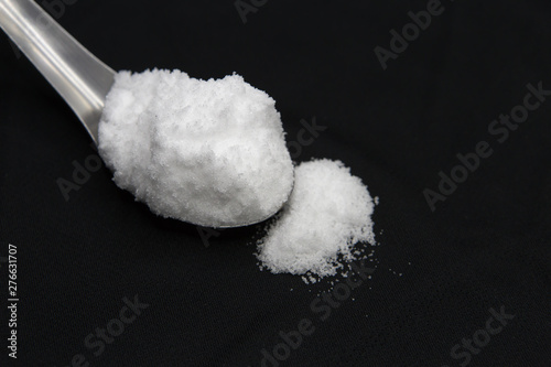 Sea salt in spoon on black background