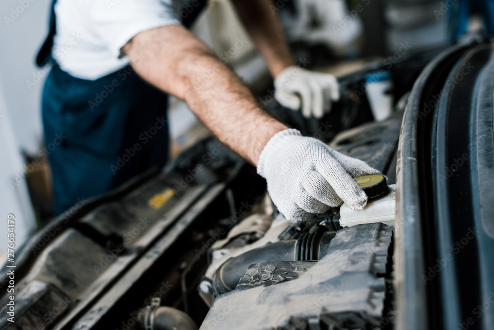cropped view of car mechanic touching bottle cap in automobile cropped view of car mechanic touching bottle cap in automobile