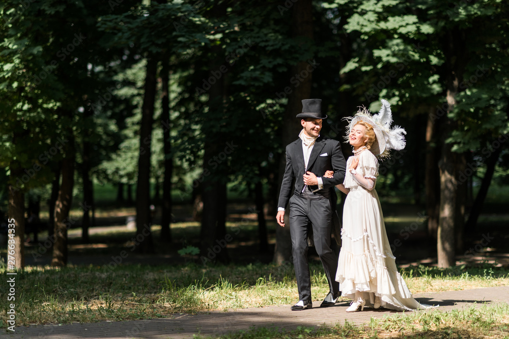 happy young victorian woman and handsome man in hat walking outside happy young victorian woman and handsome man in hat walking outside