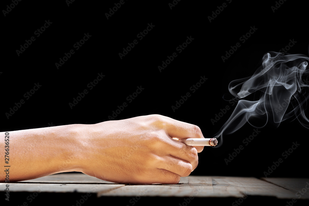 Hand holding a cigarette on wooden table