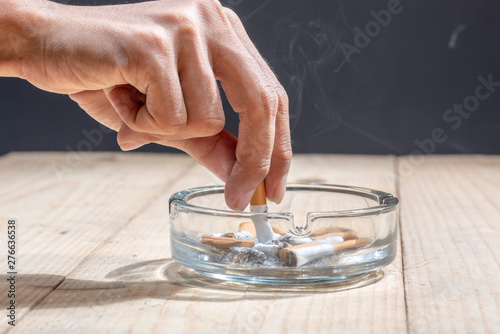 Hand stubbed out cigarette in a transparent ashtray photo
