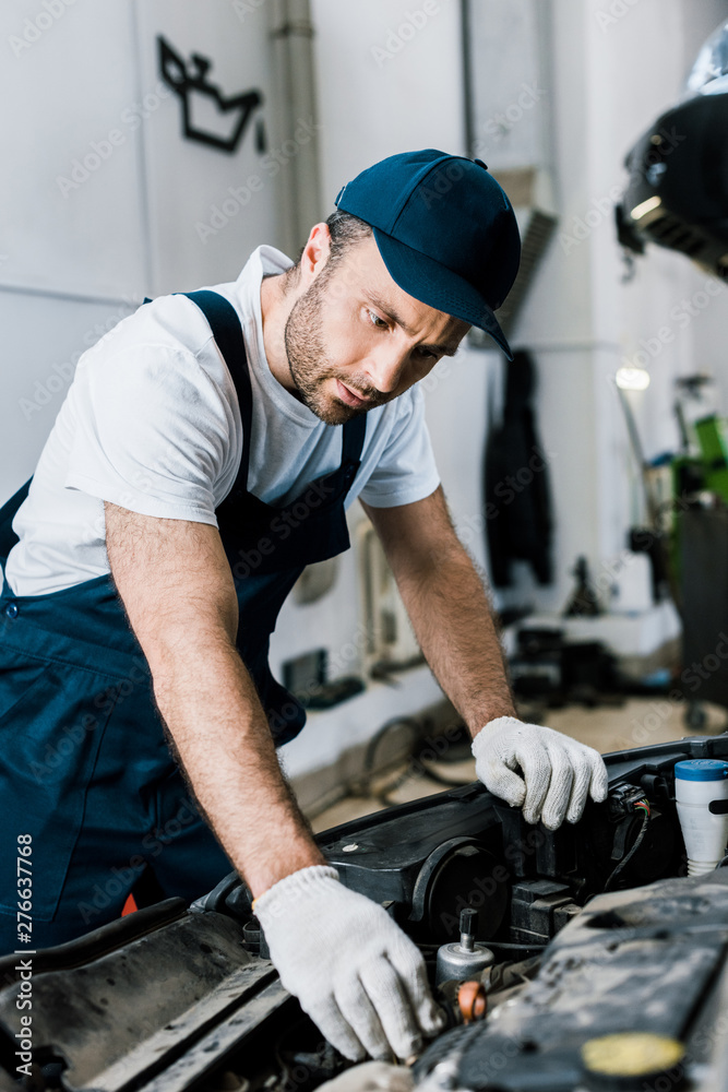 selective focus of repairman in gloves looking at car engine selective focus of repairman in gloves looking at car engine
