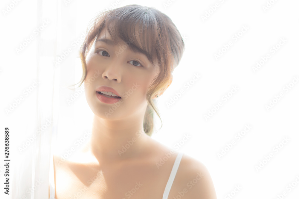 Portrait of beautiful young asian woman standing the window and smile while wake up with sunrise at morning, girl happy with freshness and cheerful, lifestyle and relax concept. Portrait of beautiful young asian woman standing the window and smile while wake up with sunrise at morning, girl happy with freshness and cheerful, lifestyle and relax concept.
