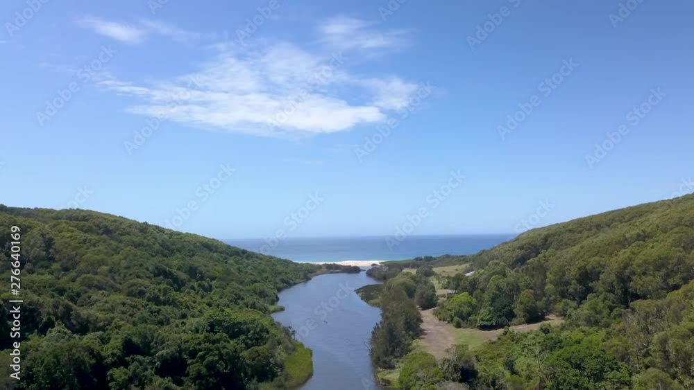 Drone flying towards Ocean through Valley with Lagoon in it Drone flying towards Ocean through Valley with Lagoon in it