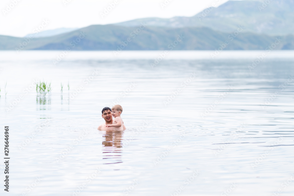 father with little son swimmind in sea, beautiful landscape sea and mountines