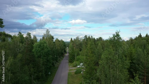 Pedestal ascending drone footage showing a road running through the forest and revealing a small town with a church and a mining tower. Filmed in realtime at 4k. photo