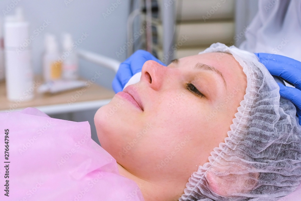 Beautician washes woman's face using cotton pads from mask. Cleaning face Beautician washes woman's face using cotton pads from mask. Cleaning face