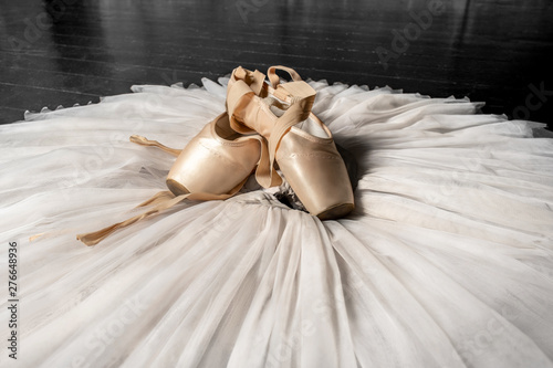 Pointe shoes. Peach shoes, ballet shoes with ribbons on a white tutu in a dance studio. Advertising ballet school. Professional ballerina outfit.