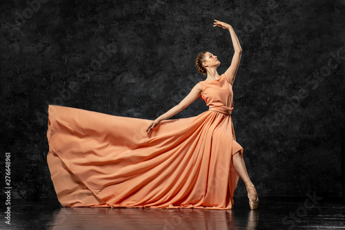 Ballerina. A young dancer dressed in a long peach dress, pointe shoes with ribbons. Performs a graceful, graceful dance movement. Beautiful classic ballet. Advertising ballet studio. Volumetric photos