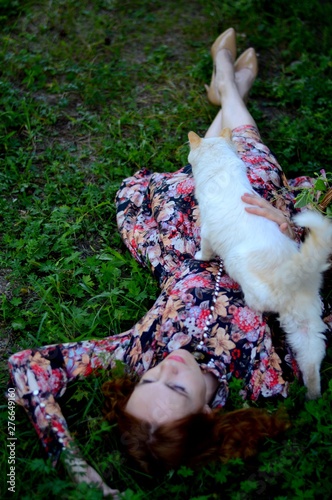 Девушка с белой кошкой лежит на траве в летний день. Прованс.