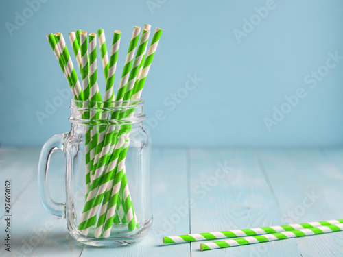 Fotografie Mason jars with green paper straws on blue wooden background