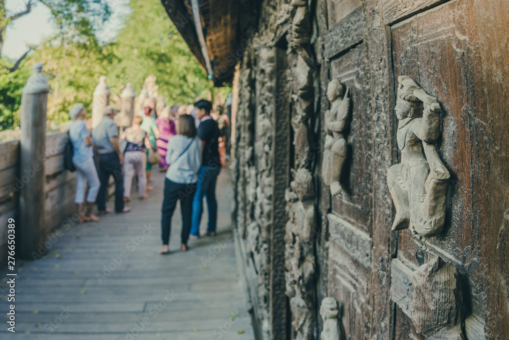 Group of tourists come to visit and take photographys at Shwe Nan Daw Kyaung (Golden Palace Monastery) in Mandalay, Myanmar. Selective focus on Wood Carving.