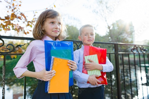 Back to school, portrait of two little school kids. Children boy and girl smile, hold school supplies