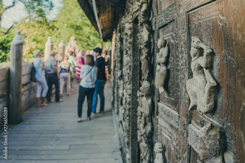 Group of tourists come to visit and take photographys at Shwe Nan Daw Kyaung (Golden Palace Monastery) in Mandalay, Myanmar. Selective focus on Wood Carving.