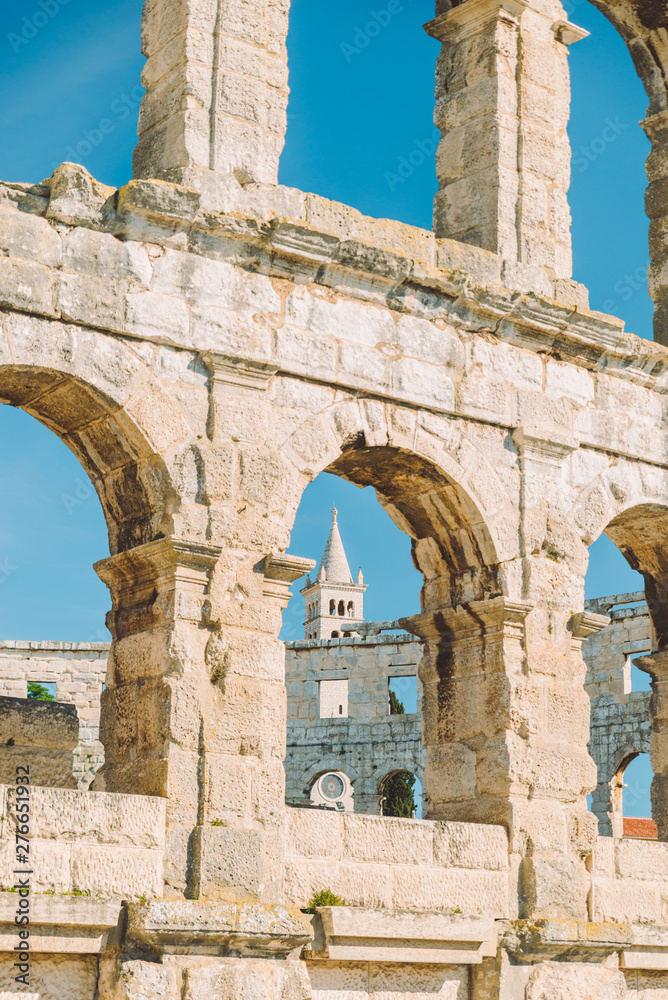 view of the church of pula through window of old roman coliseum in pula