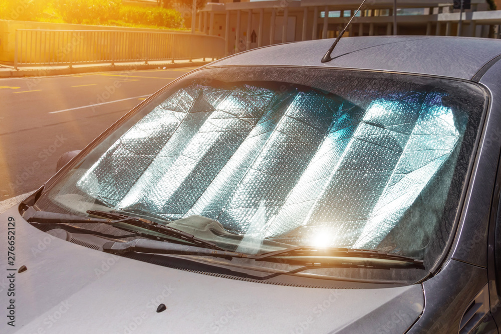 Protective reflective surface under the windshield of the passenger car parked on a hot day, heated by the sun's rays inside the car. - obrazy, fototapety, plakaty 
