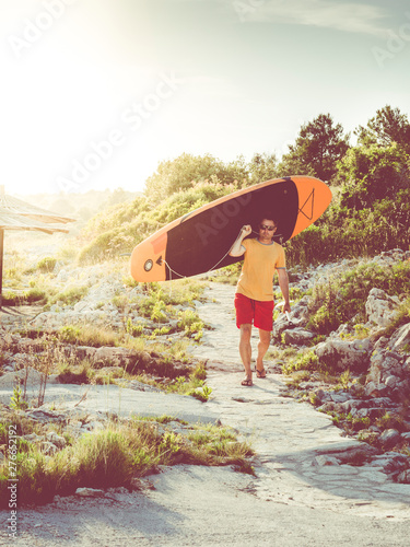 man walking on samll path after surfing in the evening photo