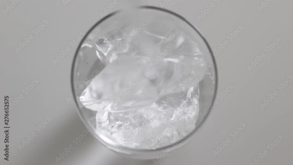 top view pouring Water into a glass with ice cubes on a white background top view pouring Water into a glass with ice cubes on a white background