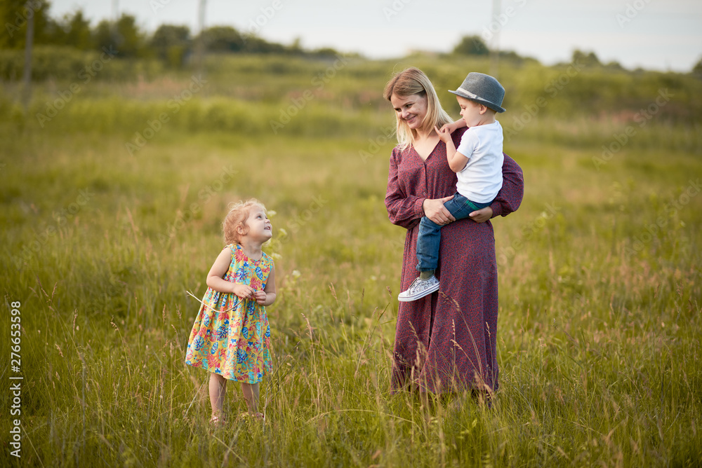 Happy family, son and girl i in wheat field at sunset. The concept of organic farming and healthy lifestyle, healthy food, happiness and joy. Cow in the background