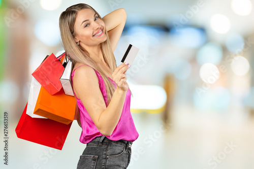 smiling young woman with shopping bags over mall background