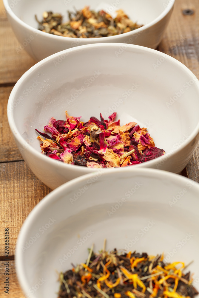 Aromatic dry tea in bowls on wooden background Aromatic dry tea in bowls on wooden background