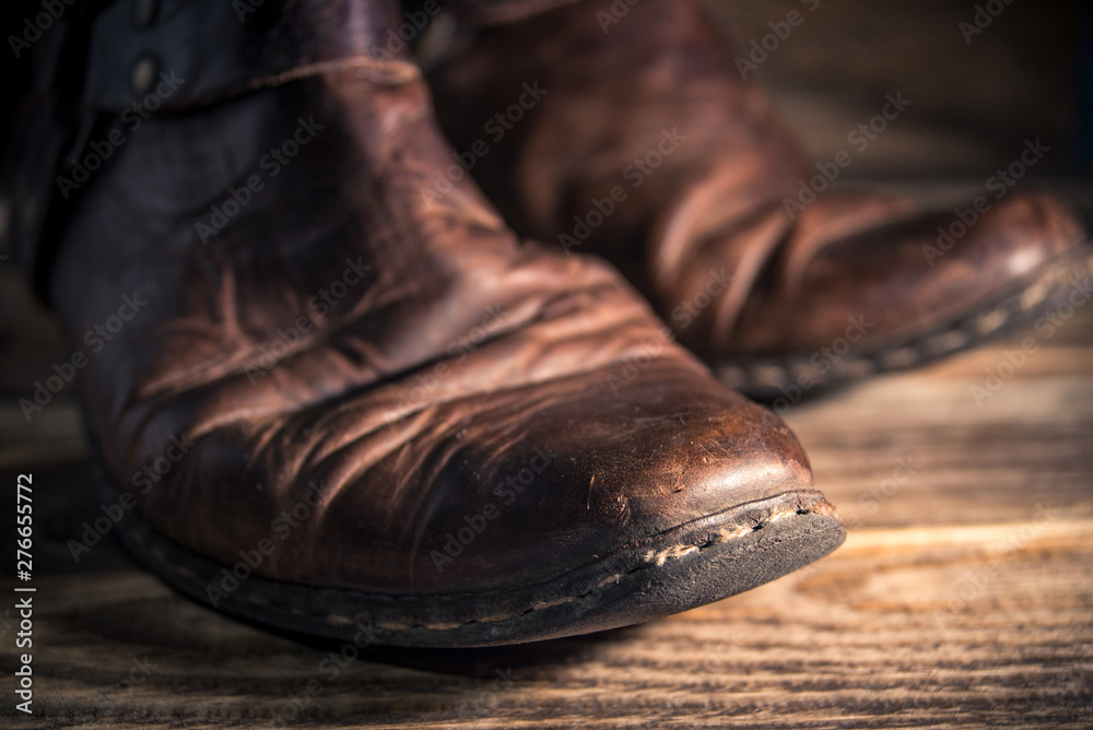 Old distressed leather shoes on wooden background