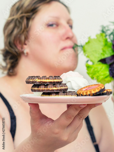 A young woman who is overweight chooses between healthy food and sweets, copies the space. Diet, healthy eating, weight loss, slimmimg photo