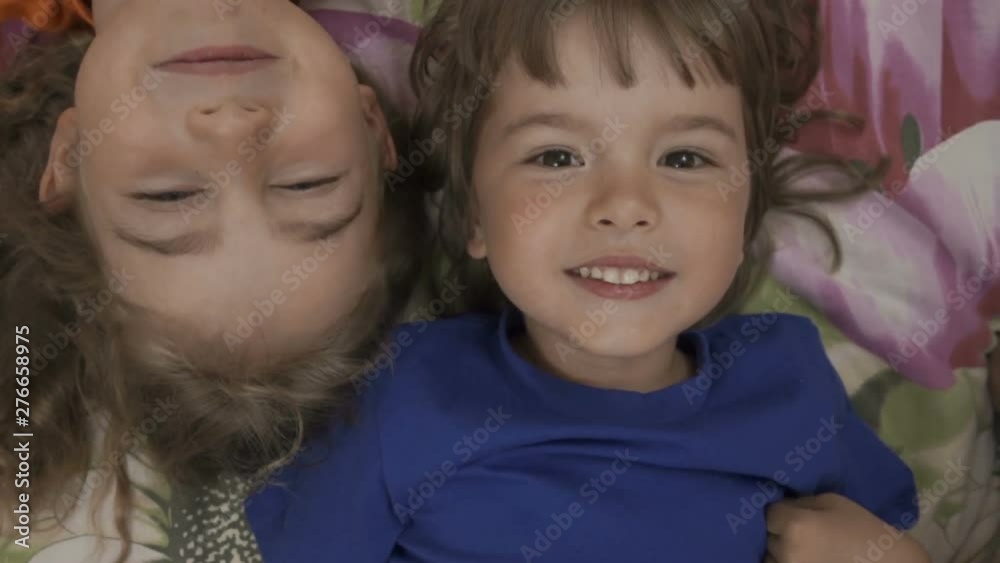 Family selfie. Excited young children playing lying on the bed and taking a selfie. Little brother and sister monkeying on camera and kissing. Family taking a selfie with a smartphone. Close up. Family selfie. Excited young children playing lying on the bed and taking a selfie. Little brother and sister monkeying on camera and kissing. Family taking a selfie with a smartphone. Close up.