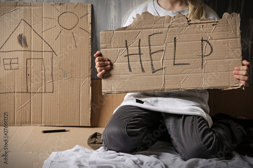 Homeless little girl begging for help near wall photo