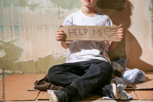 Homeless little boy begging for help near wall photo