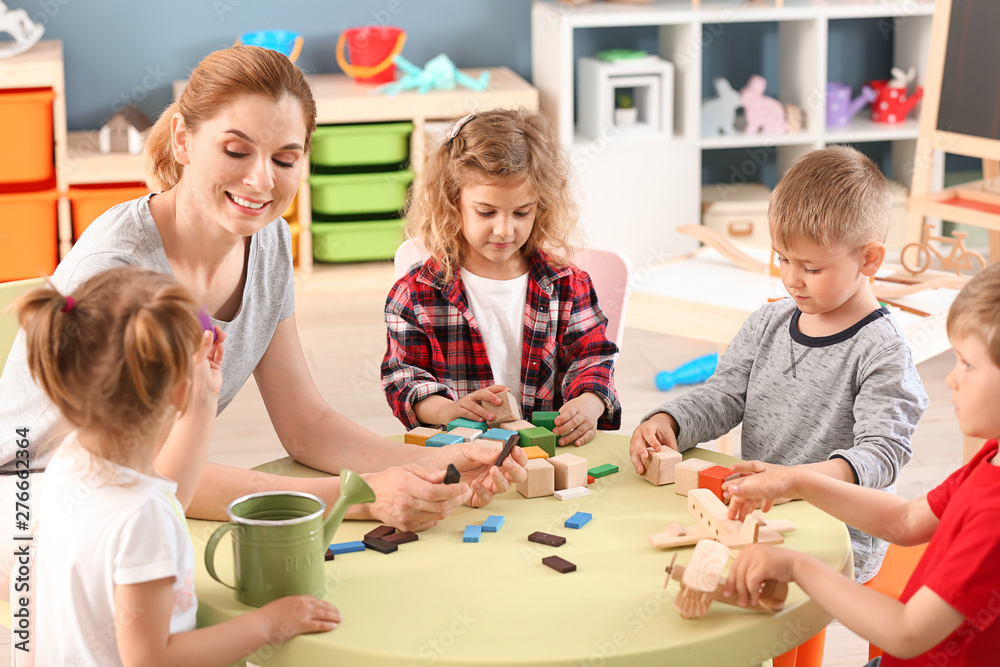 Fototapeta premium Nursery teacher with cute little children in kindergarten