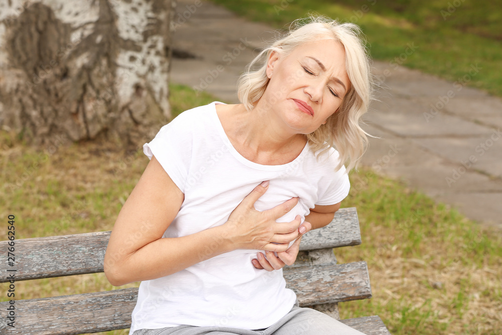 Obraz premium Mature woman suffering from heart attack outdoors