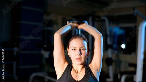 The girl is engaged in the gym. Exercise for triceps with a dumbbell.