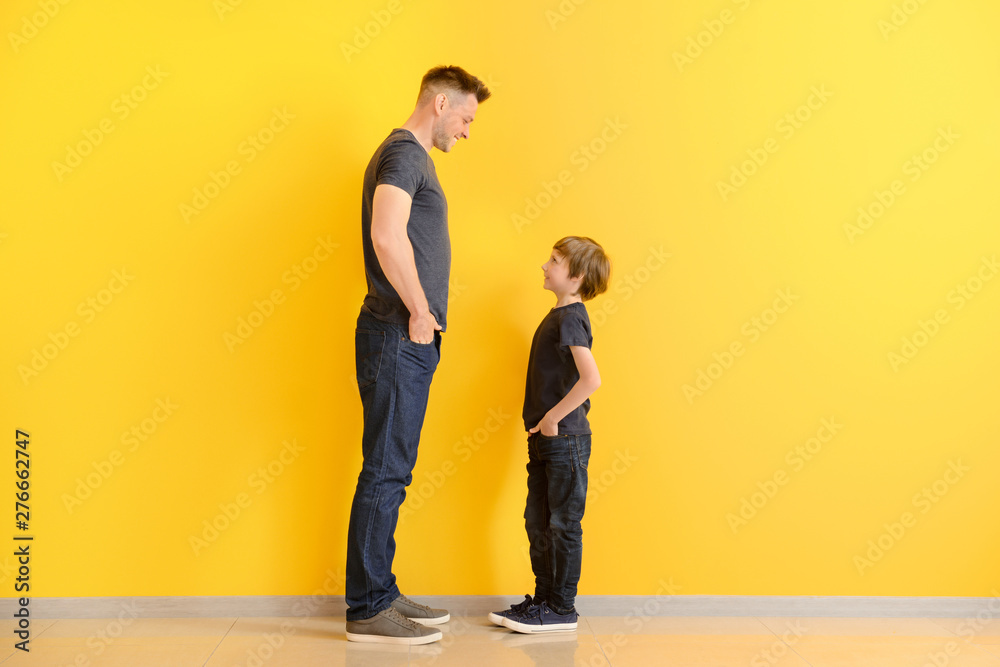 Portrait of father and son near color wall - obrazy, fototapety, plakaty 