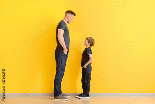 Portrait of father and son near color wall