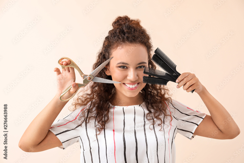 Fototapeta premium Beautiful African-American hairdresser on light background