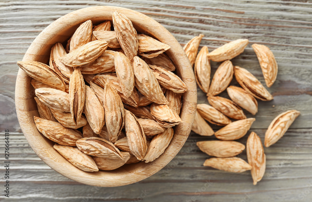 Bowl with unpeeled almond nuts on wooden background Bowl with unpeeled almond nuts on wooden background