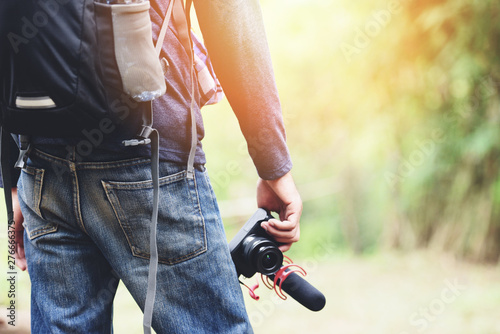 Traveler man holding the camera on nature forest tourist on holiday vacation trips adventure travel hike people backpacks