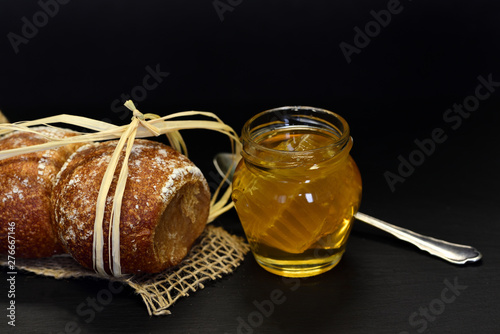 Frisches Brot mit Faden umwickelt und Honig vor dunklem Hintergrund photo