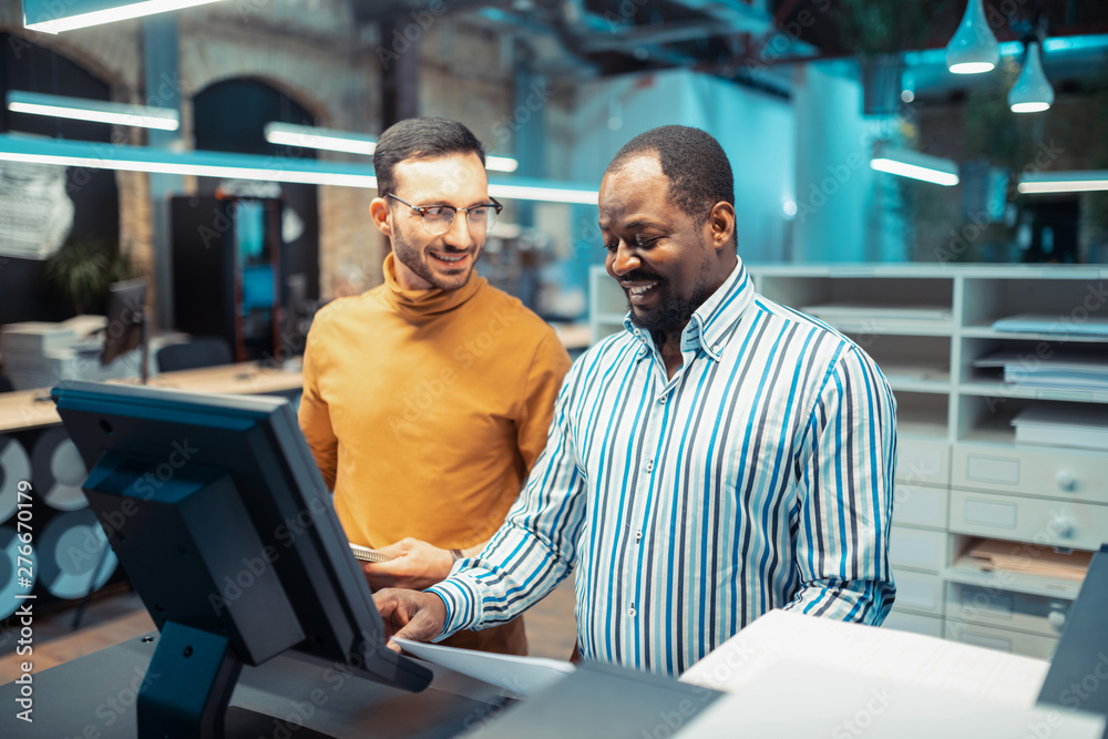 Man wearing glasses talking to his dark-skinned colleague Man wearing glasses talking to his dark-skinned colleague