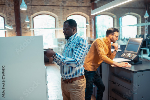 Dark-skinned publisher feeling busy working in printing office