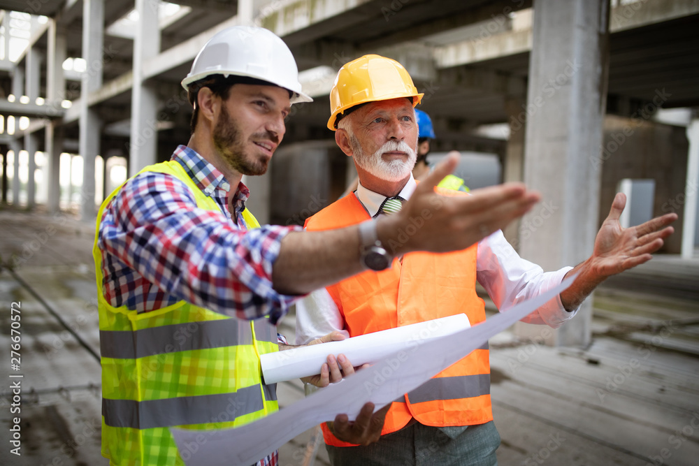 Engineer and construction site manager dealing with blueprints and plans