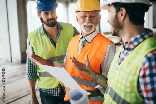 Engineer, foreman and worker discussing in building construction site