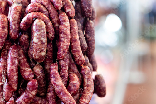 Background with vertically hanged dried sausages in the market pavilion, copy space - image