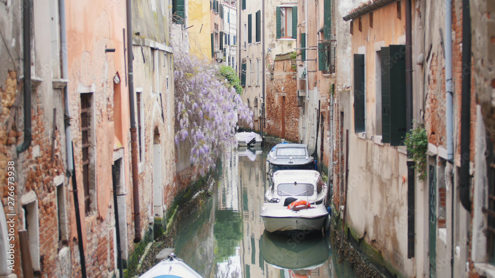 Narrow streets of Venice - canal filled with water - moored boats