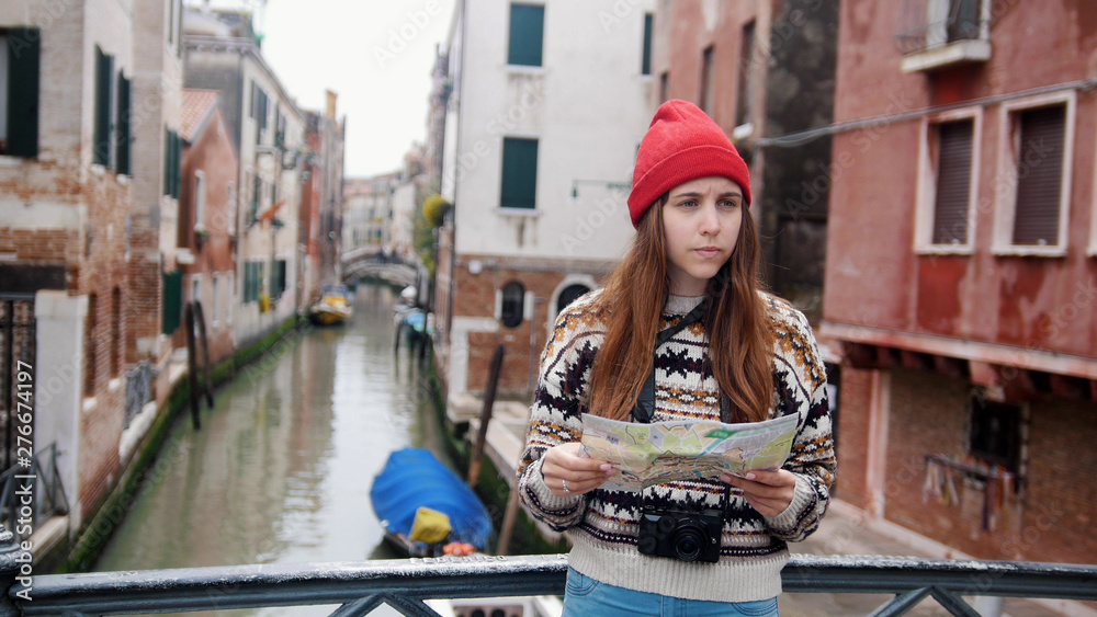 Obraz premium A young confused woman standing above the water channel and looking at the map - Venice, Italy